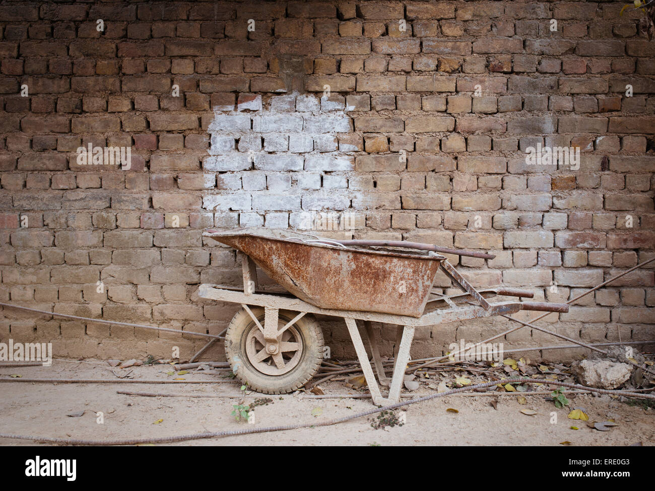 Empty wheelbarrow near brick wall Stock Photo