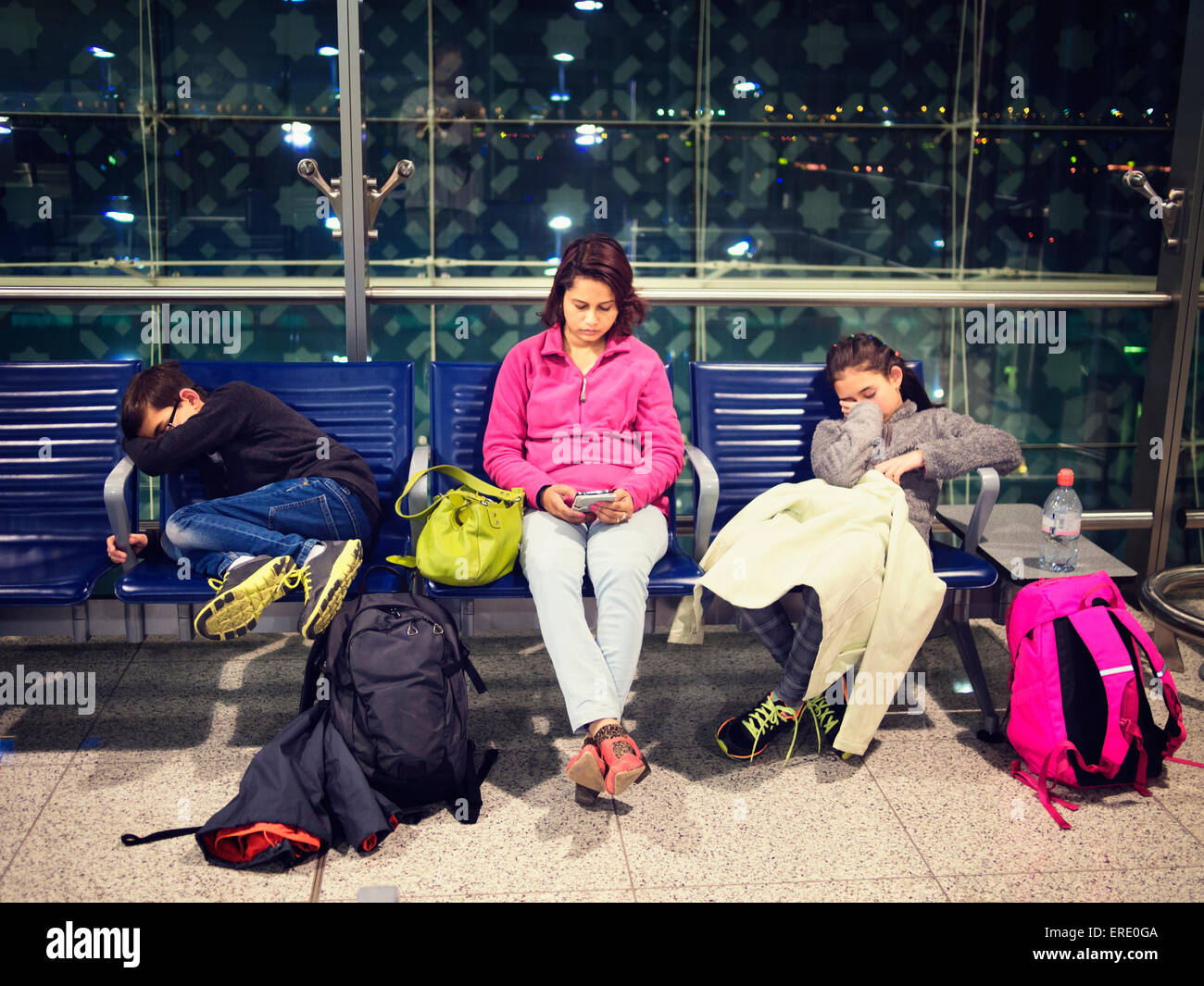 Mother and children relaxing in airport waiting area Stock Photo