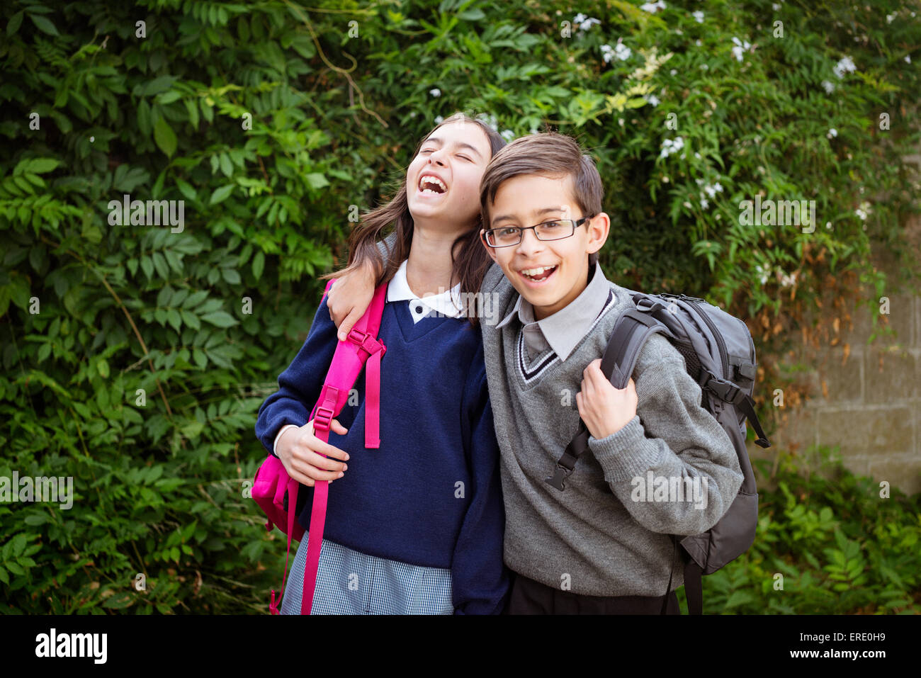 Mixed race brother and sister laughing in school uniforms Stock Photo