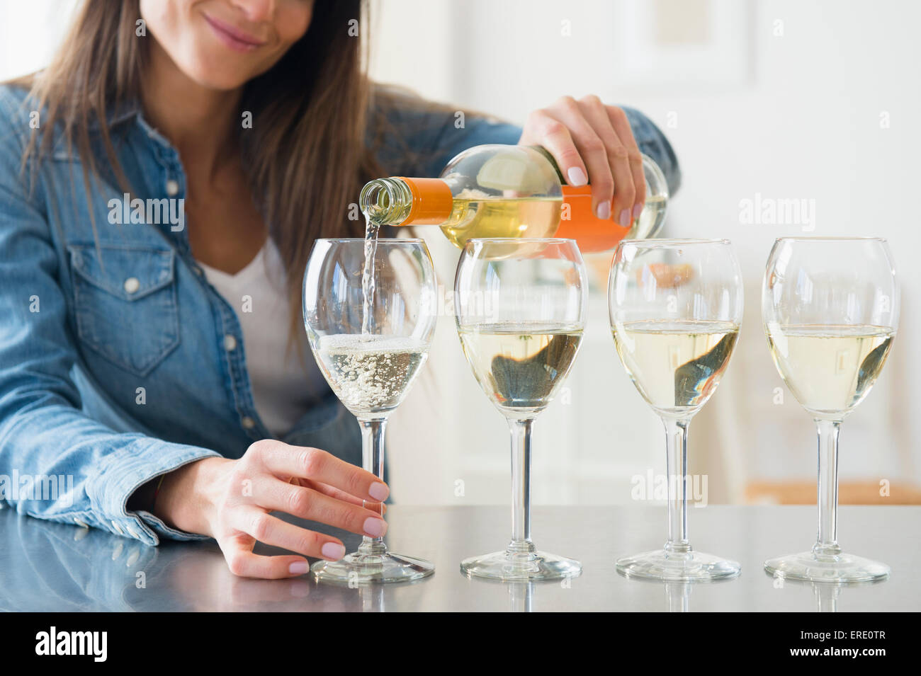 Caucasian woman pouring glasses of white wine Stock Photo