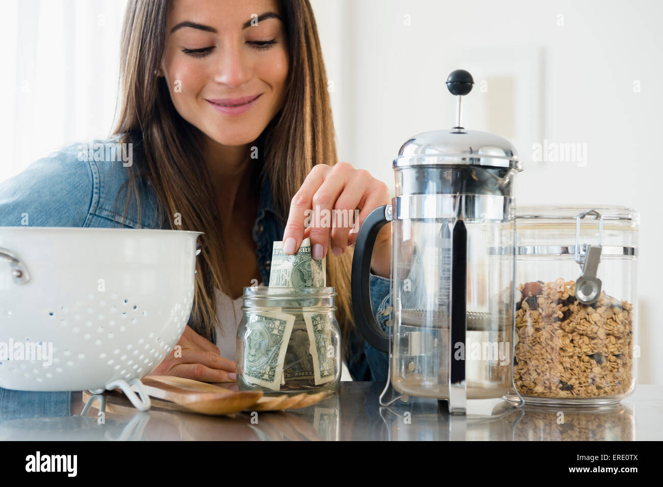Caucasian woman putting money in jar Stock Photo