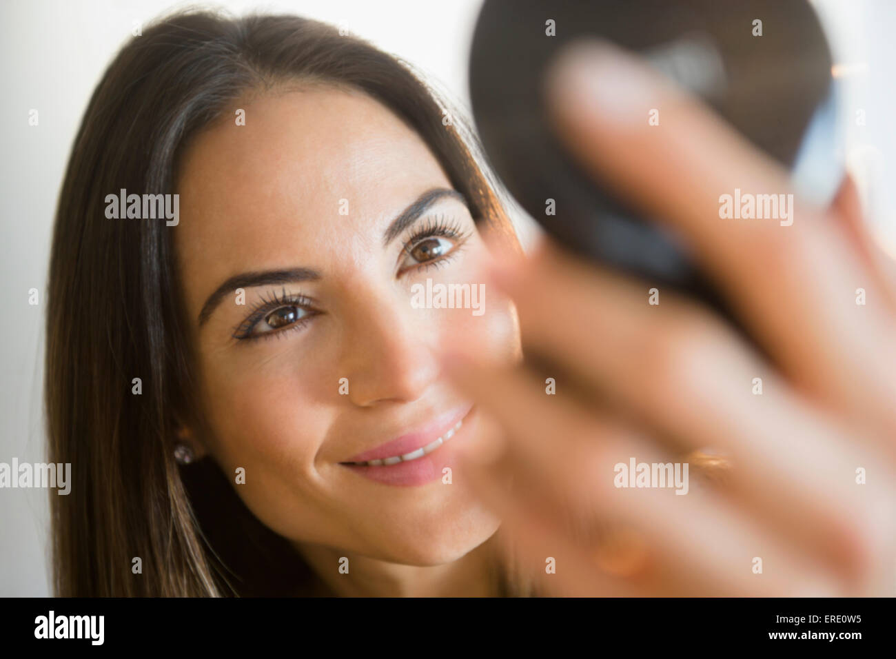 Caucasian woman admiring herself in compact mirror Stock Photo
