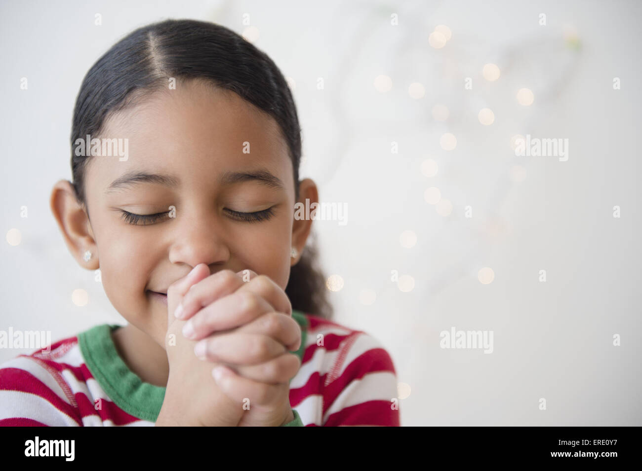 Close up of mixed race girl praying at Christmas Stock Photo