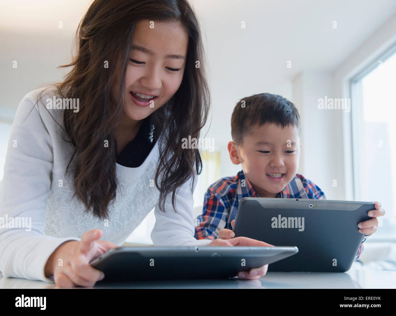 Asian brother and sister using digital tablets at table Stock Photo - Alamy