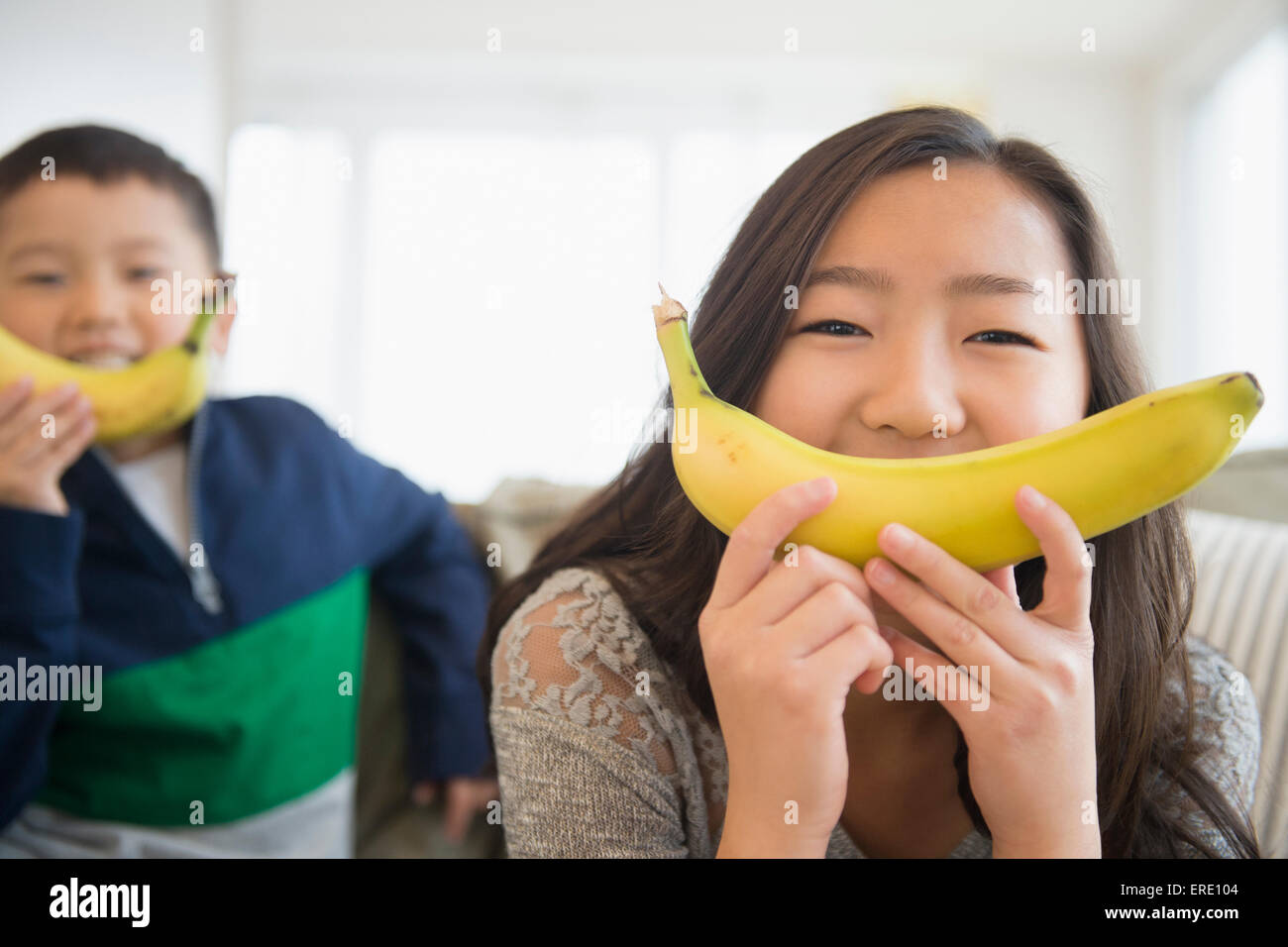 Asian children holding bananas in front of faces for smiles Stock Photo