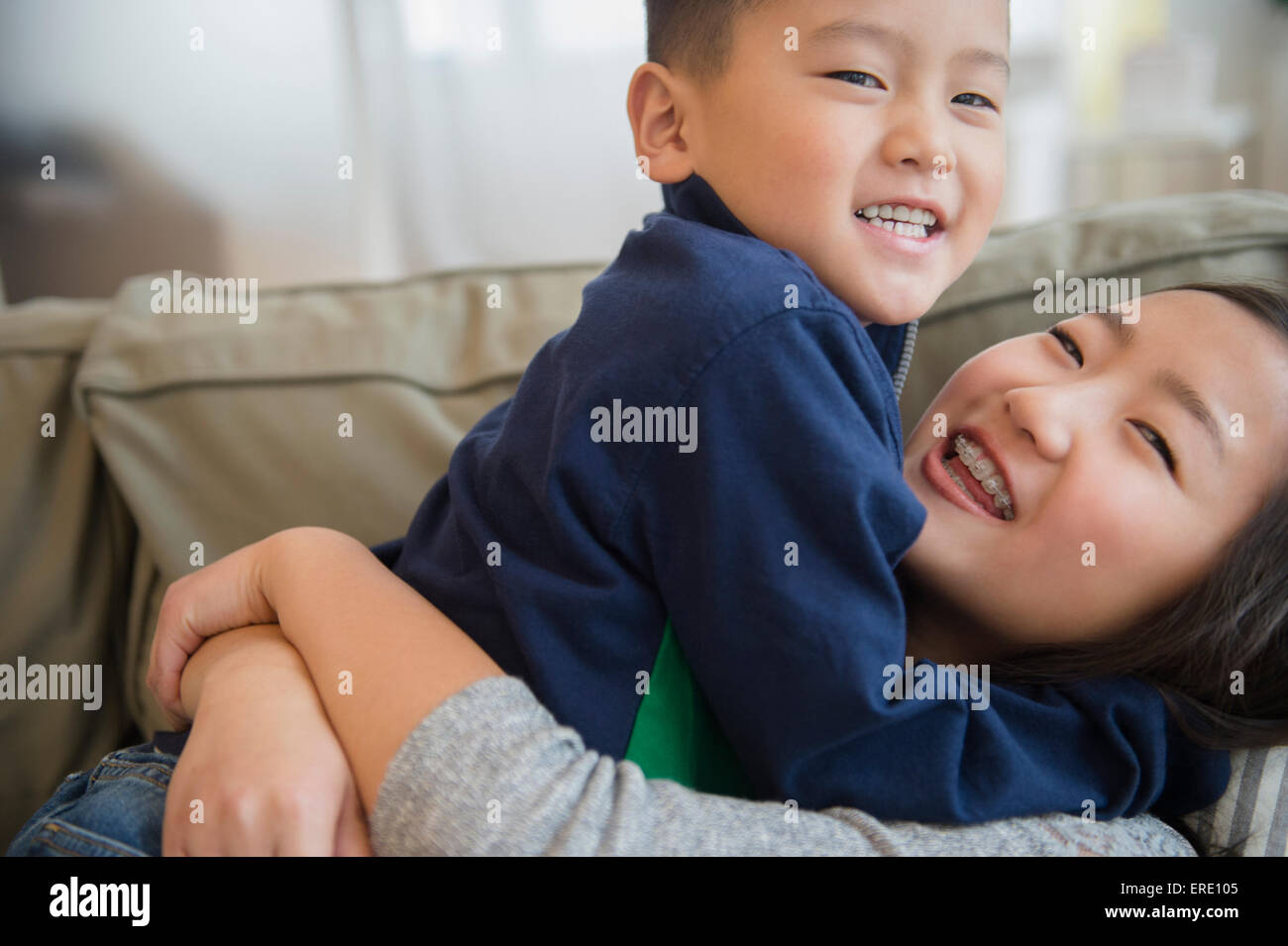 Asian brother and sister playing on sofa Stock Photo