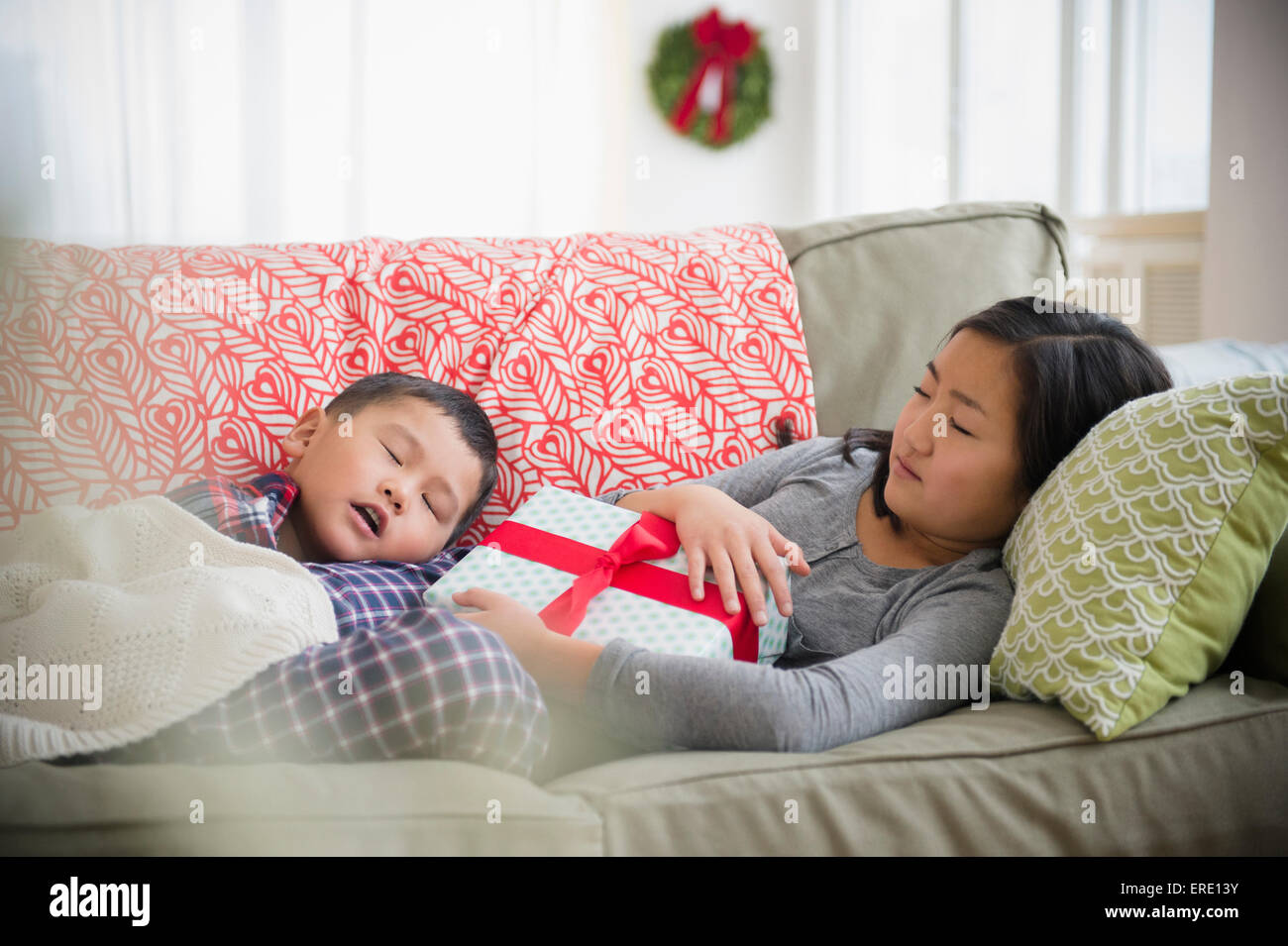 Asian brother and sister napping on sofa with Christmas gift Stock Photo