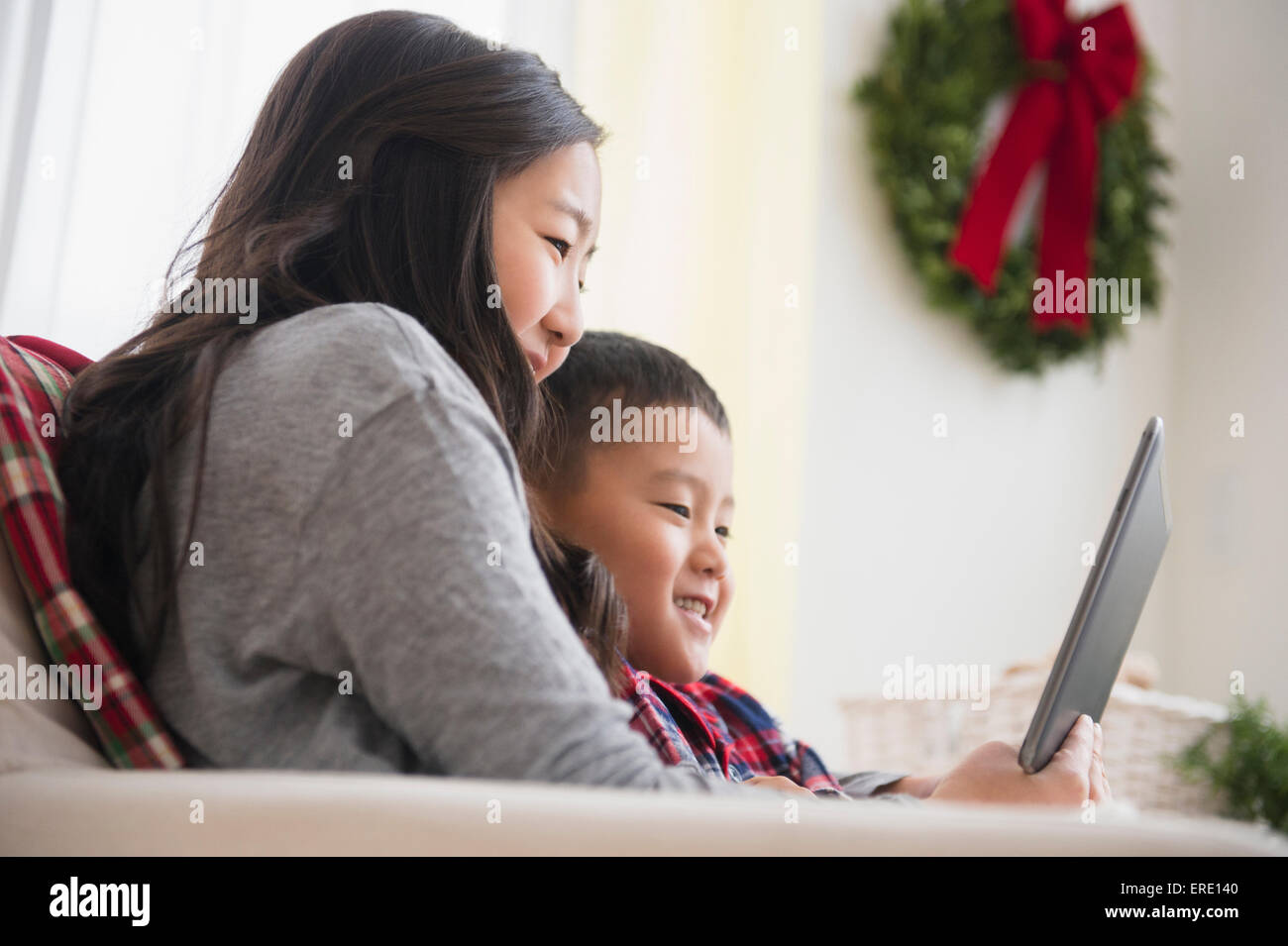 Asian brother and sister using laptop on sofa Stock Photo - Alamy