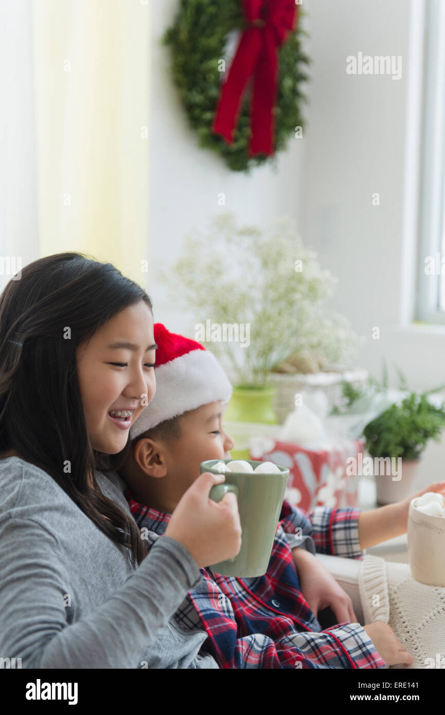 Asian brother and sister drinking hot cocoa at Christmas Stock Photo
