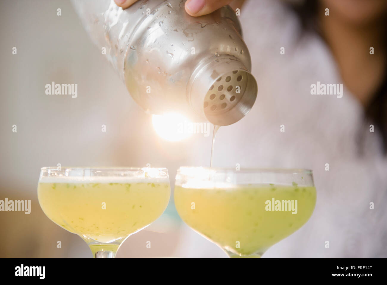 Pacific Islander woman pouring cocktails from shaker Stock Photo