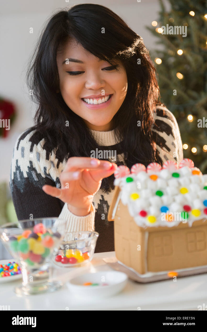 Pacific Islander woman decorating gingerbread house Stock Photo