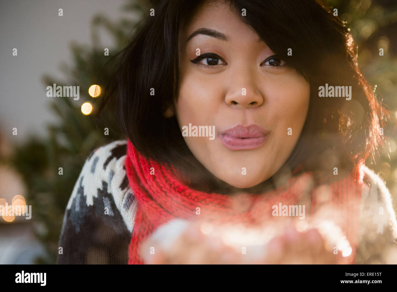 Pacific Islander woman blowing snow at Christmas Stock Photo