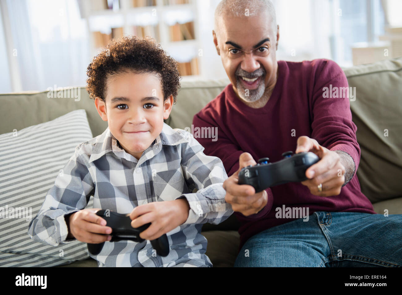 Mixed race grandfather and grandson playing video games Stock Photo