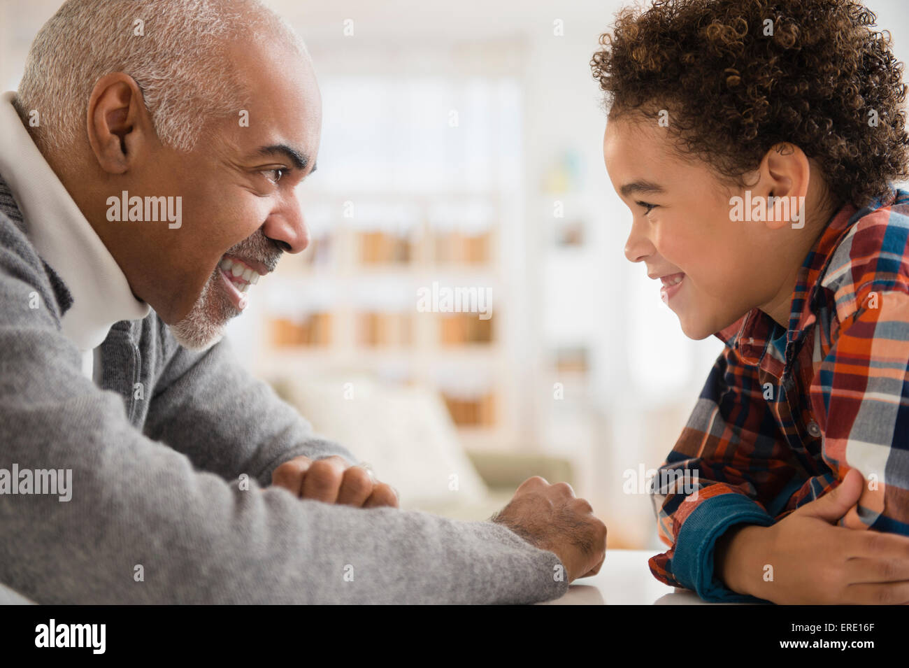 Mixed race grandfather and grandson having staring contest Stock Photo