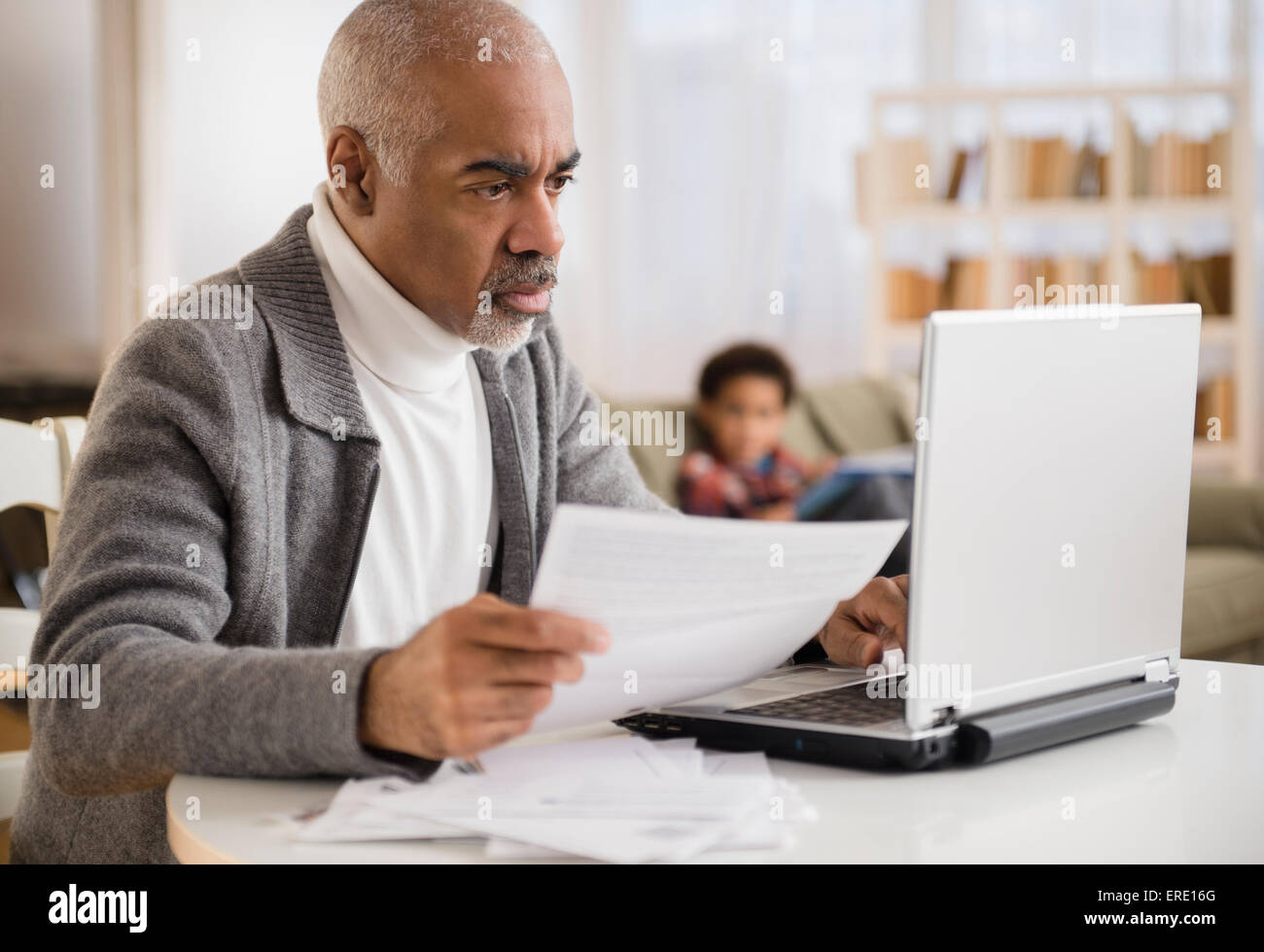 Mixed race man paying bills on laptop Stock Photo