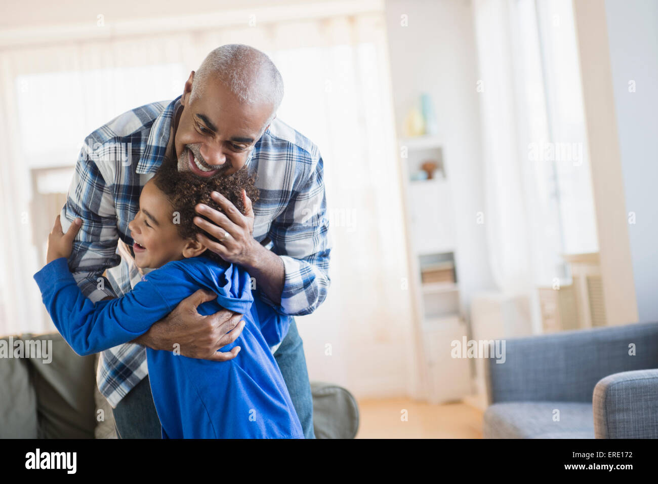 Mixed race grandfather and grandson hugging in living room Stock Photo