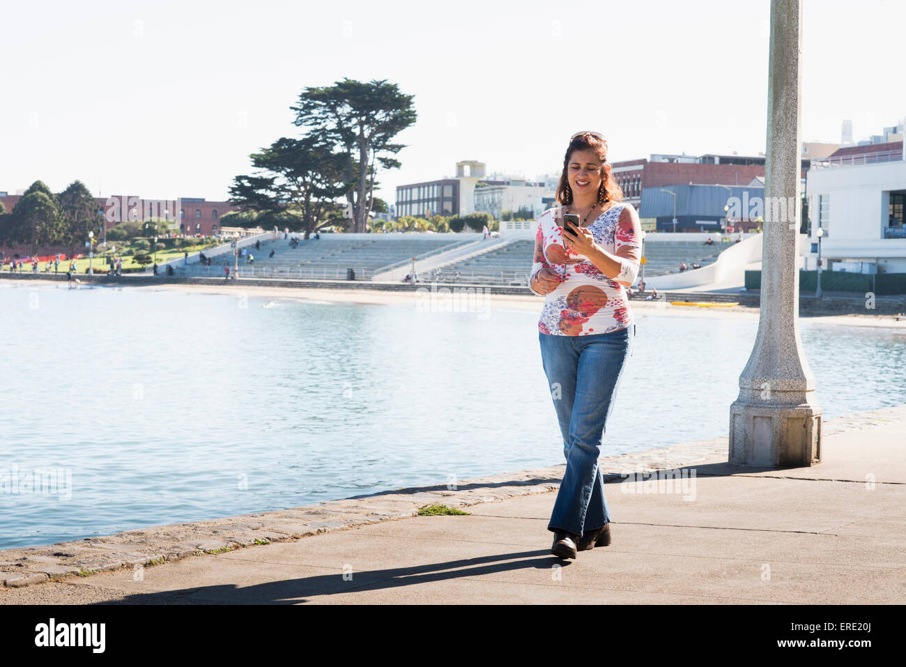 Hispanic woman texting on cell phone at waterfront Stock Photo - Alamy