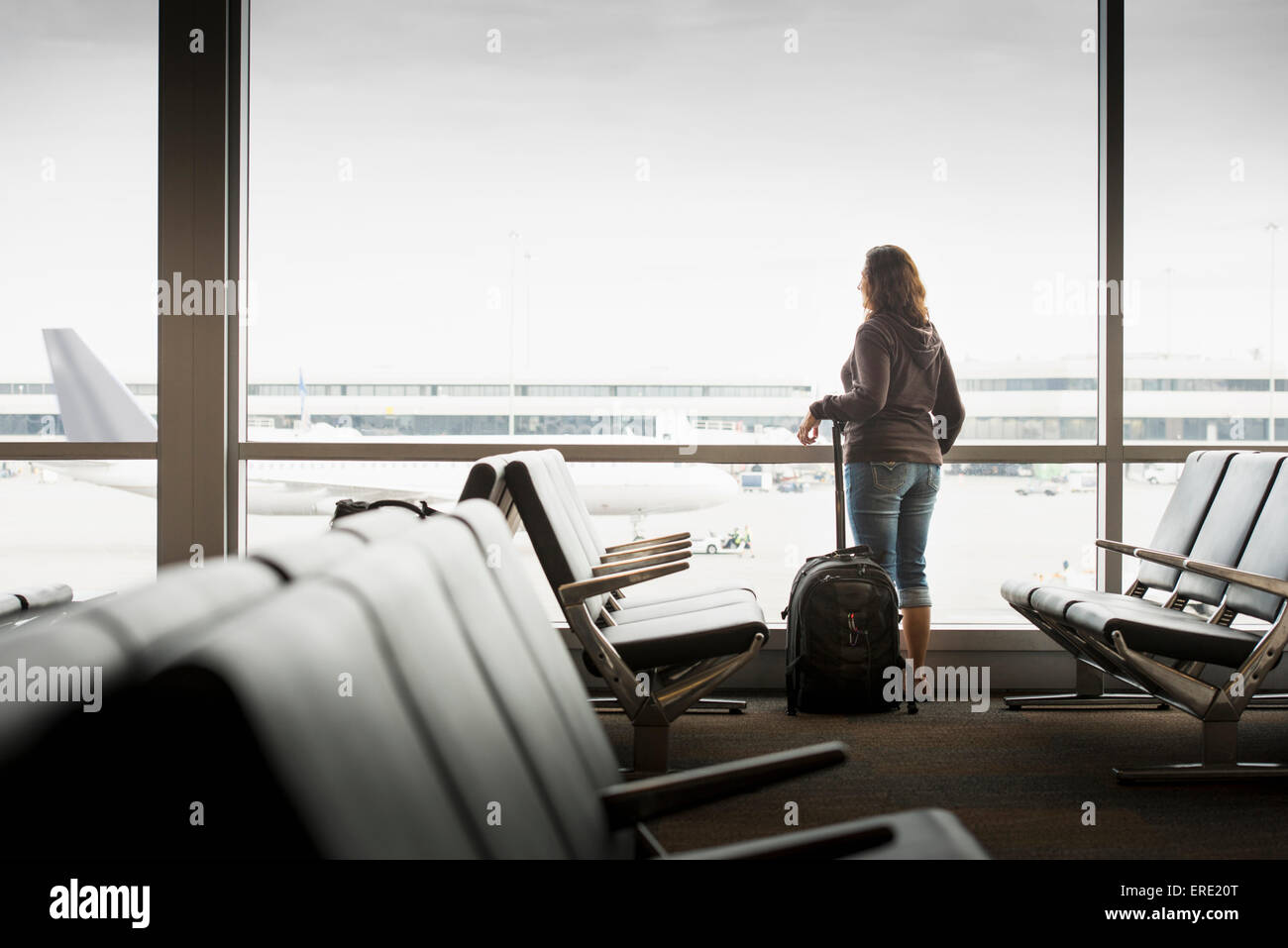 Hispanic woman looking out airport window Stock Photo