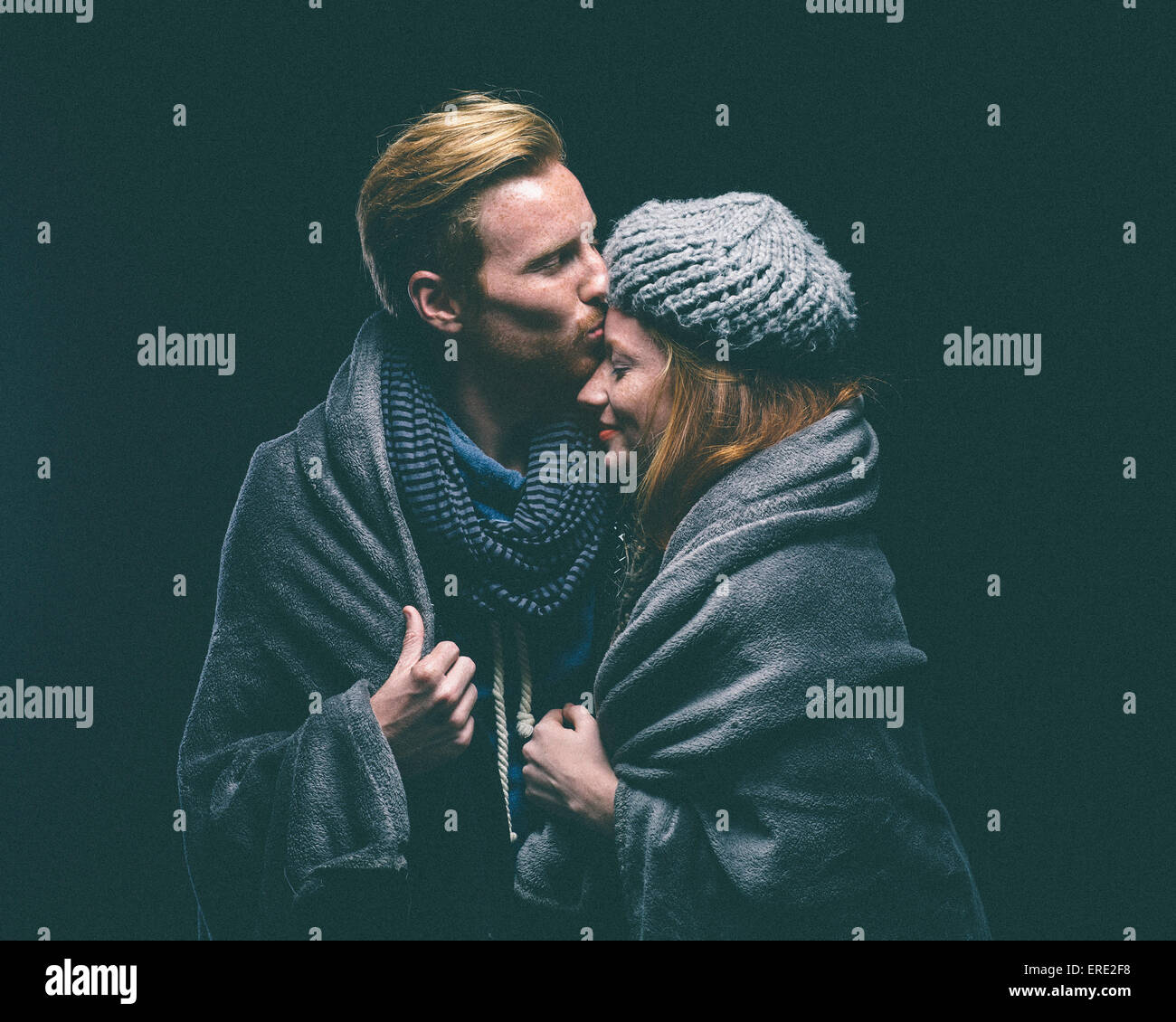 Smiling couple wrapped in blanket kissing Stock Photo Alamy
