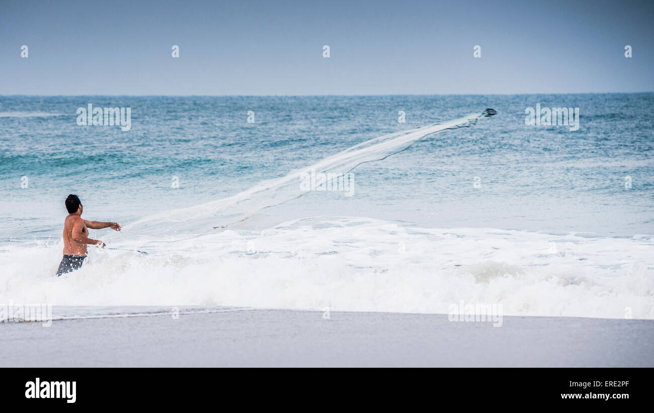 Man watching boat in ocean waves from beach Stock Photo