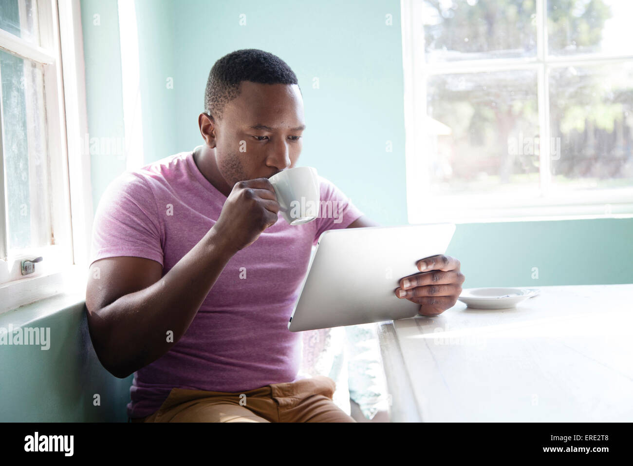 Black man drinking coffee and using digital tablet Stock Photo