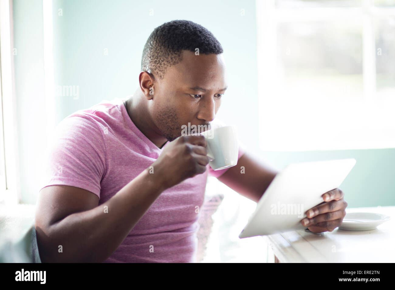 Black man drinking coffee using digital tablet Stock Photo
