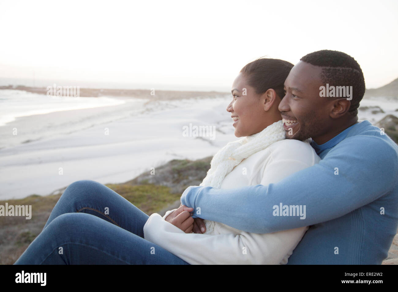 Couple hugging on cliffs over beach Stock Photo