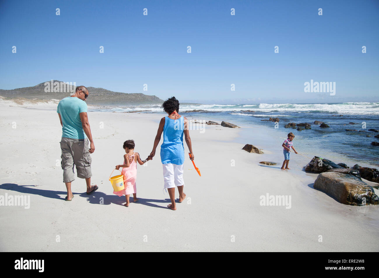Mixed race family walking on beach Stock Photo