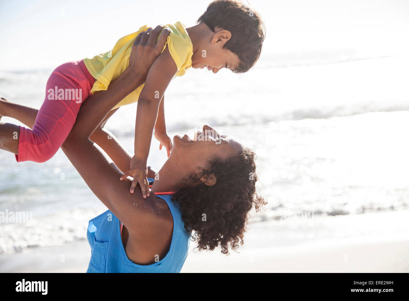 Mixed race mother lifting daughter at beach Stock Photo