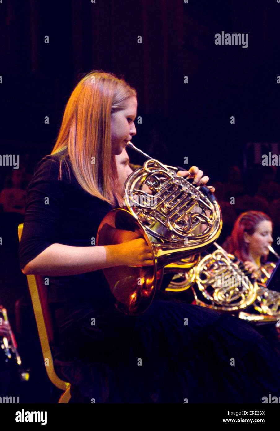 Female French horn player playing in a youth symphony orchestra at one of the Schools Prom series of concerts at the Royal Stock Photo