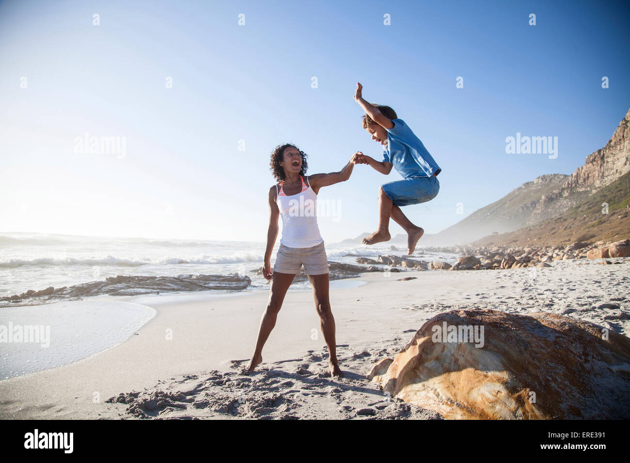 Mixed race mother and son playing on beach Stock Photo