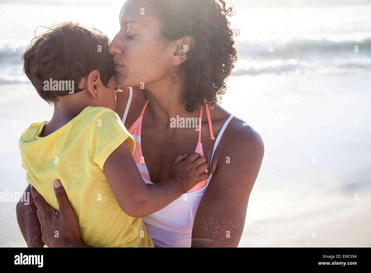 Mixed race mother kissing daughter on beach Stock Photo