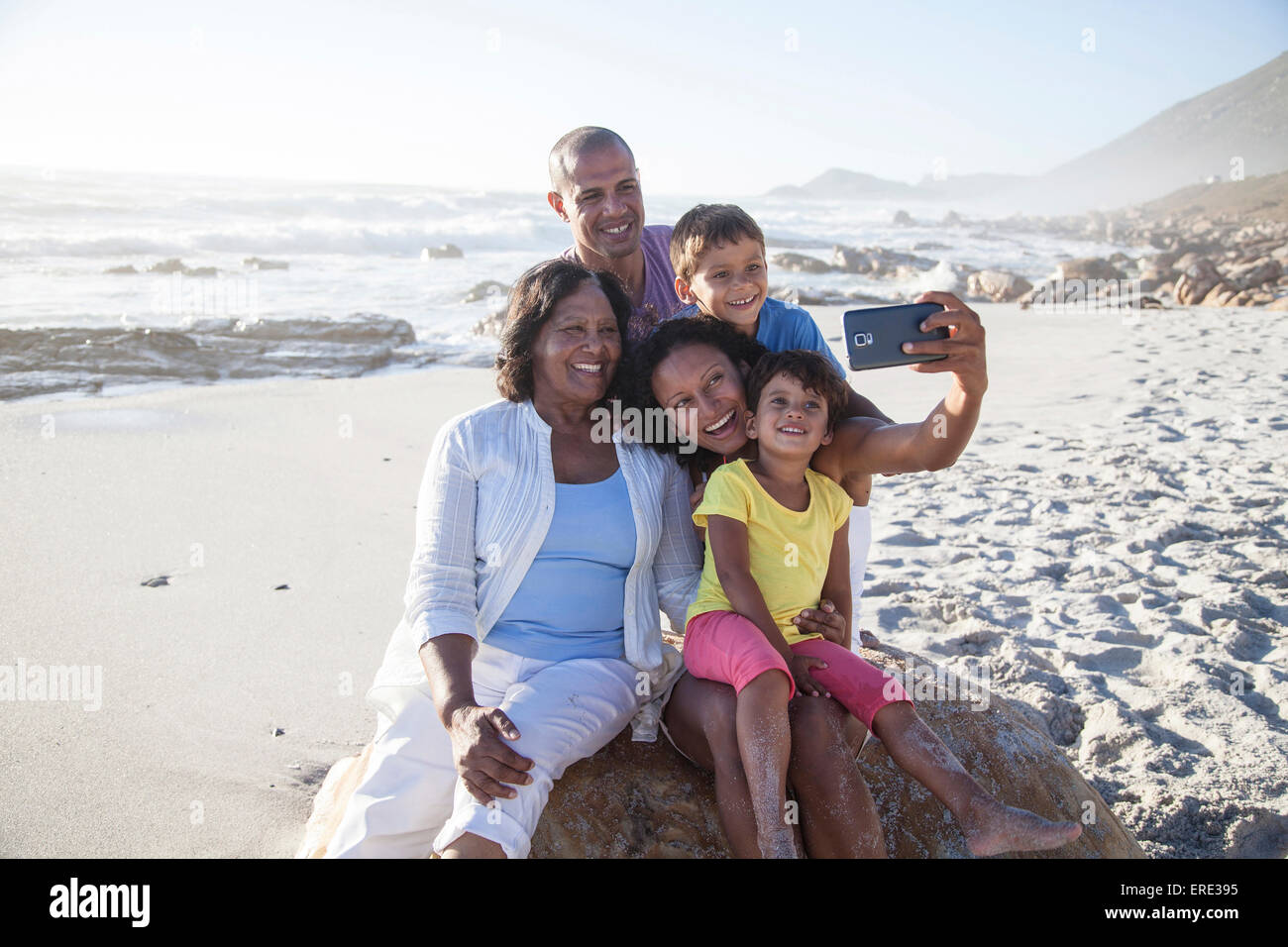 Mixed race multi-generation family taking cell phone selfie on beach Stock Photo