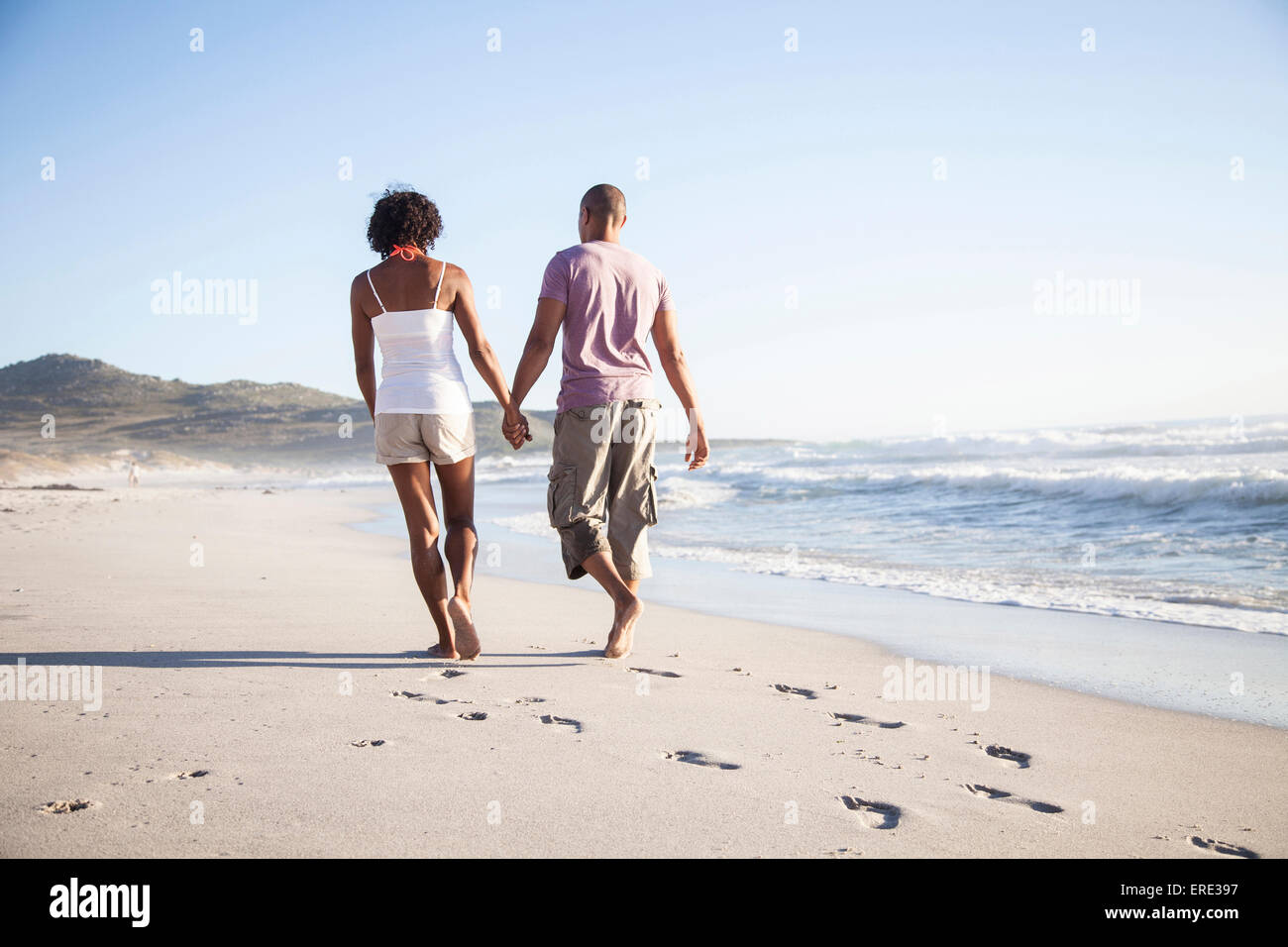 Mixed race couple walking on beach Stock Photo