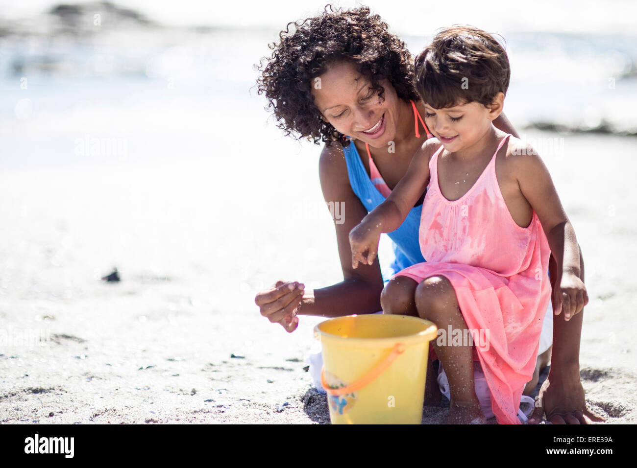 Mixed race mother and daughter playing on beach Stock Photo
