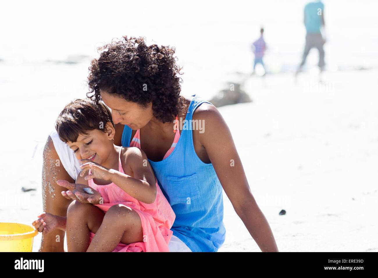 Mixed race mother and daughter playing on beach Stock Photo