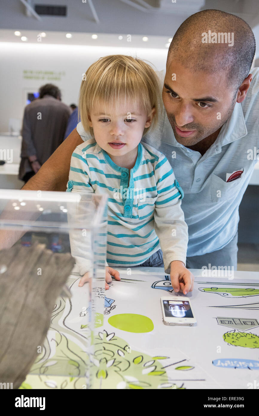 Hispanic father and son using cell phone in museum Stock Photo