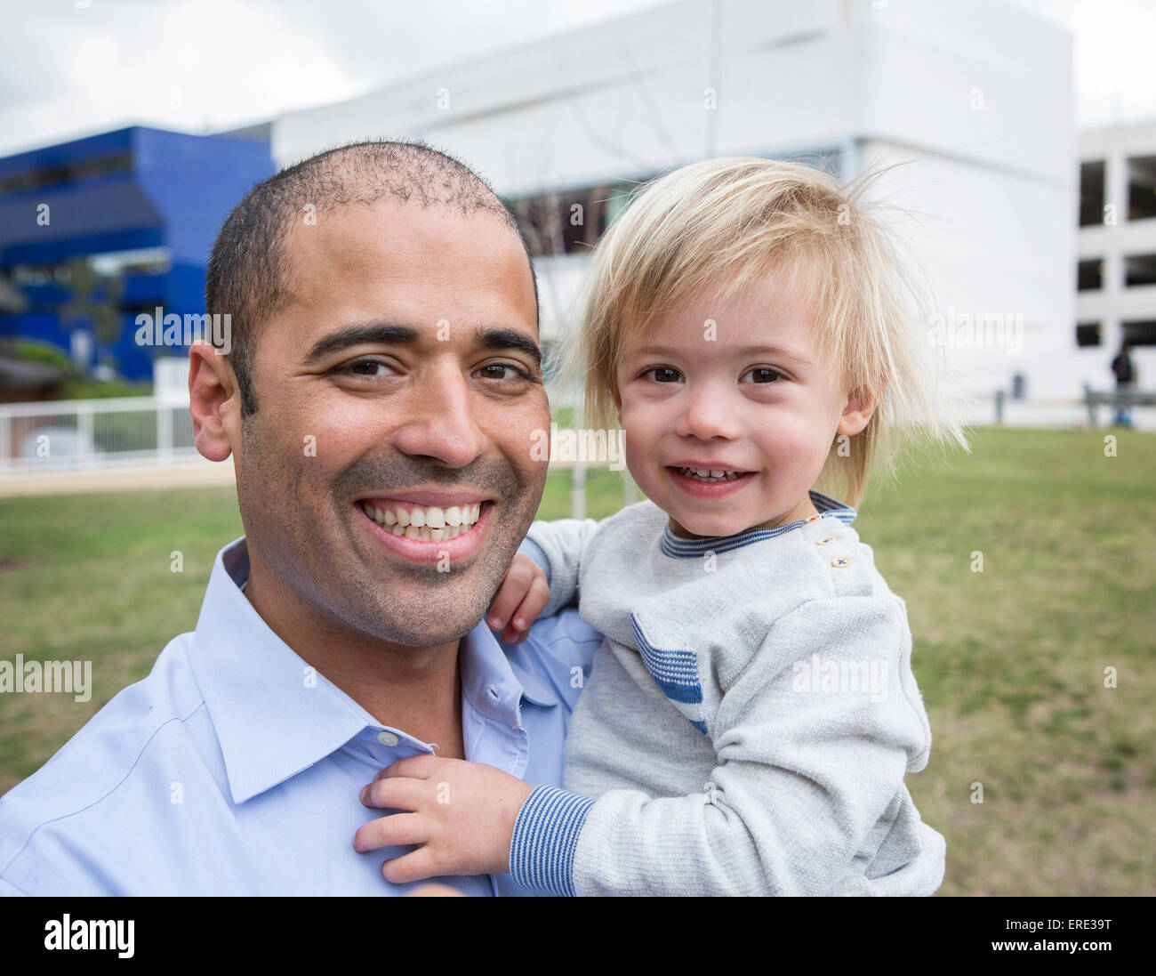 Hispanic father and son smiling in field Stock Photo