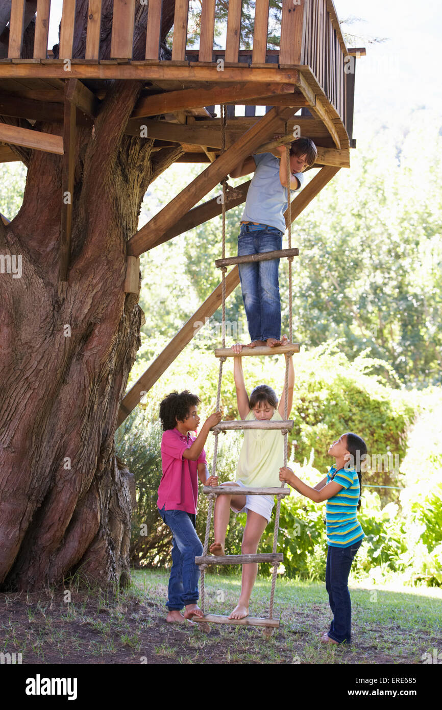 Group Of Children Climbing Rope Ladder To Treehouse Stock Photo Alamy