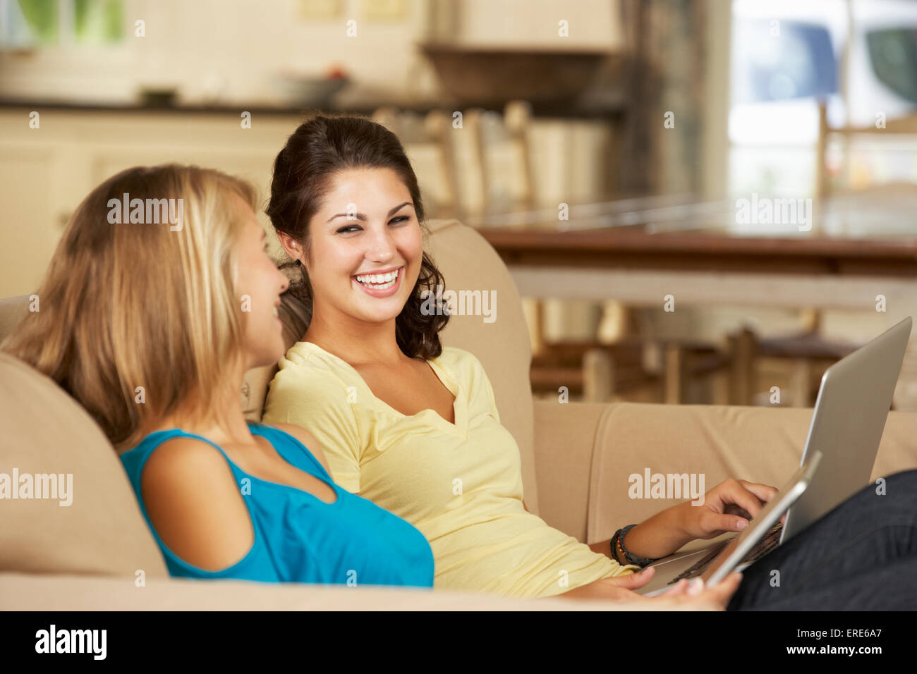 Two Teenage Girls Sitting On Sofa At Home Using Tablet Computer And ...