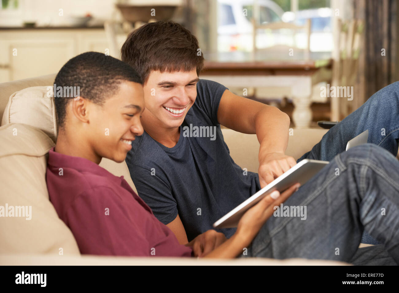 Two Teenage Boys Sitting On Sofa At Home Using Tablet Computer Stock ...