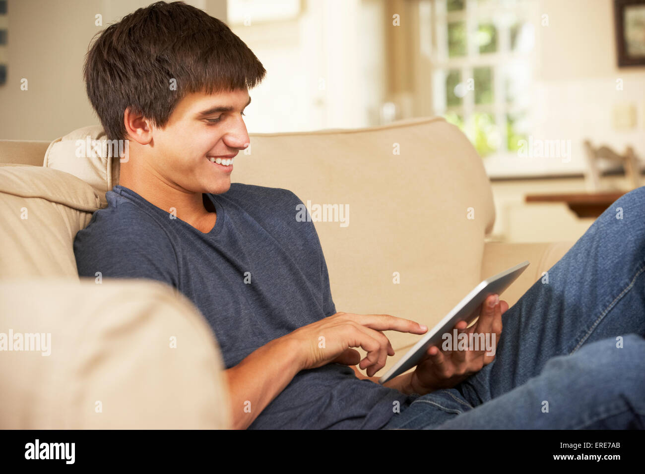 Teenage Boy Sitting On Sofa At Home Using Tablet Computer Stock Photo ...