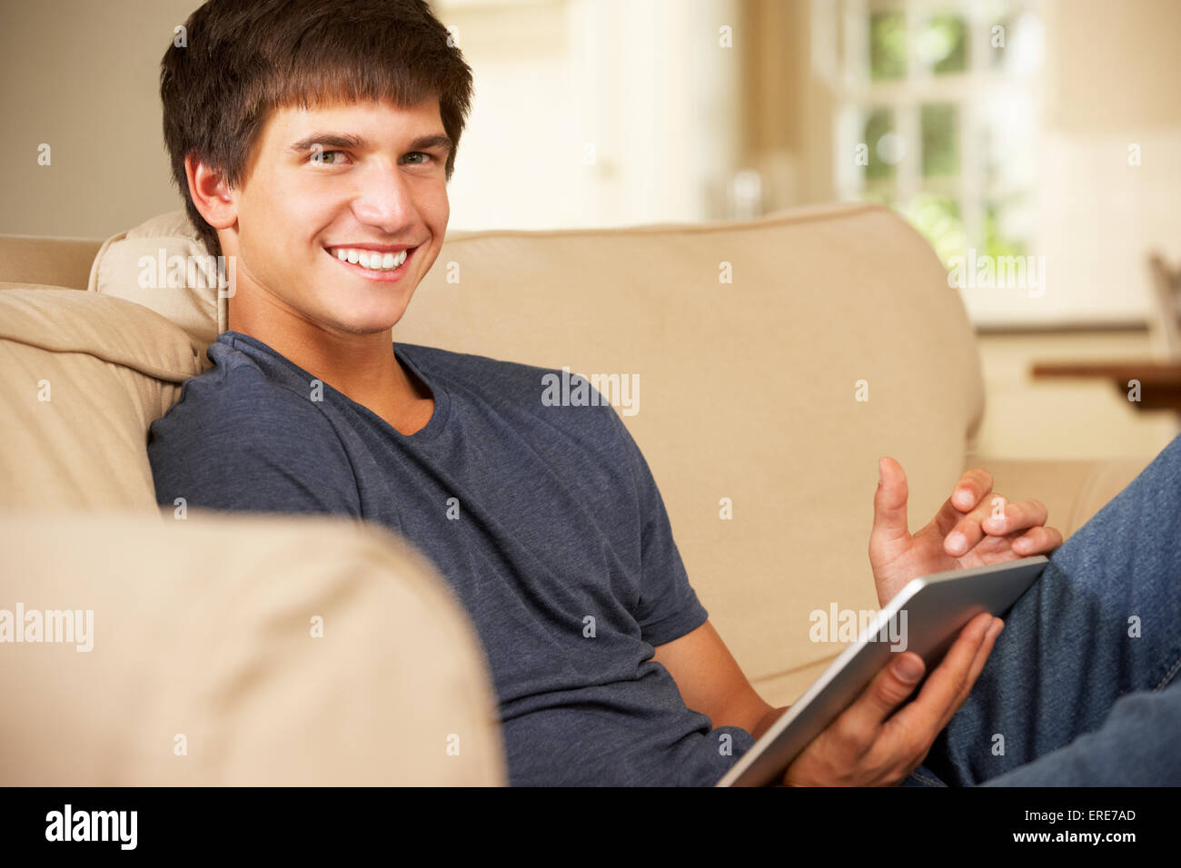 Teenage Boy Sitting On Sofa At Home Using Tablet Computer Stock Photo ...