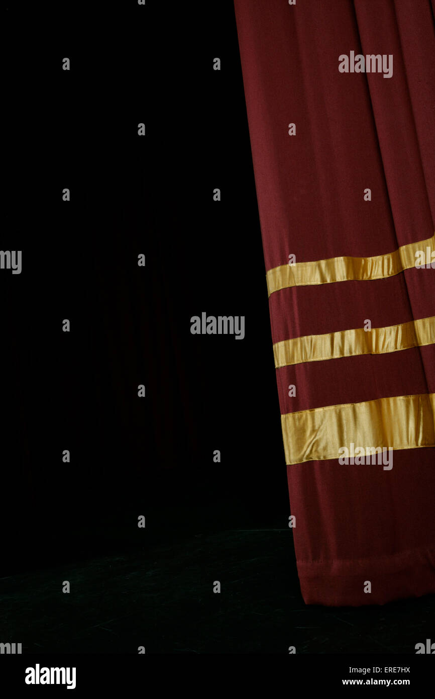 Single Red stage curtain with gold stripes, partly open Stock Photo