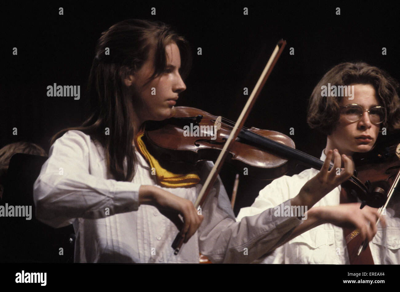 Girls playing violin with bow in youth orchestra Stock Photo