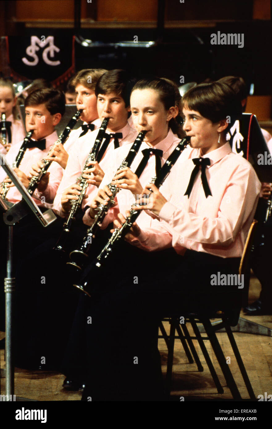 Boys playing clarinet in youth orchestra All seated and wearing same shirts Stock Photo