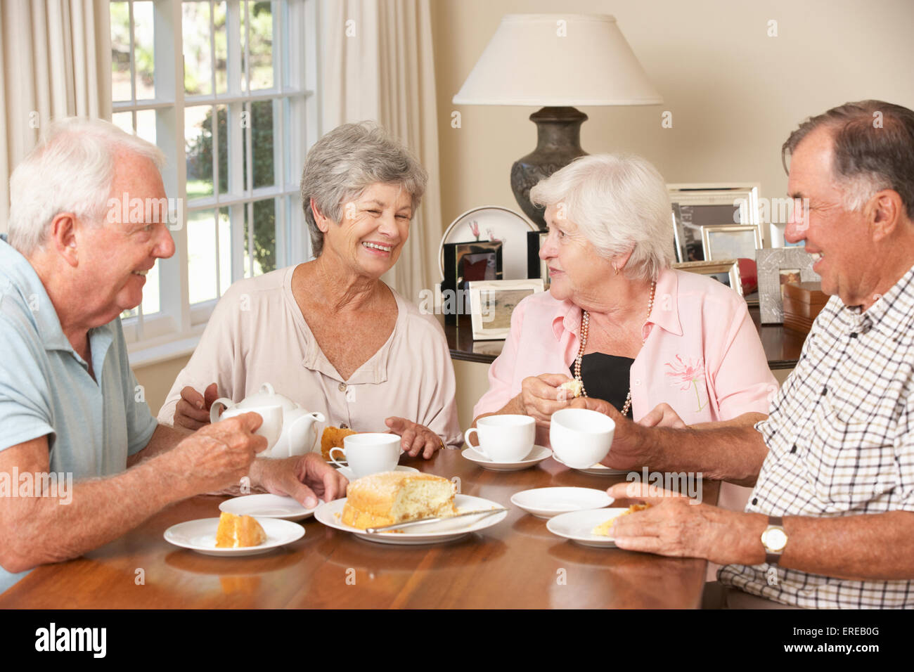 Group Of Senior Couples Enjoying Afternoon Tea Together At Home Stock Photo
