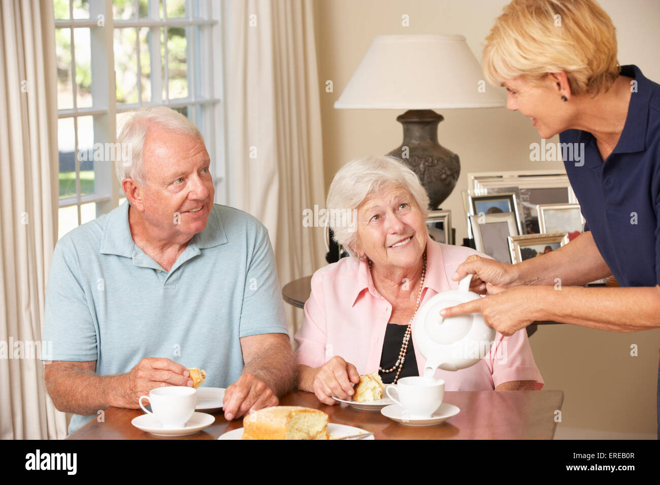 Senior Couple Enjoying Afternoon Tea Together At Home With Home Help Stock Photo