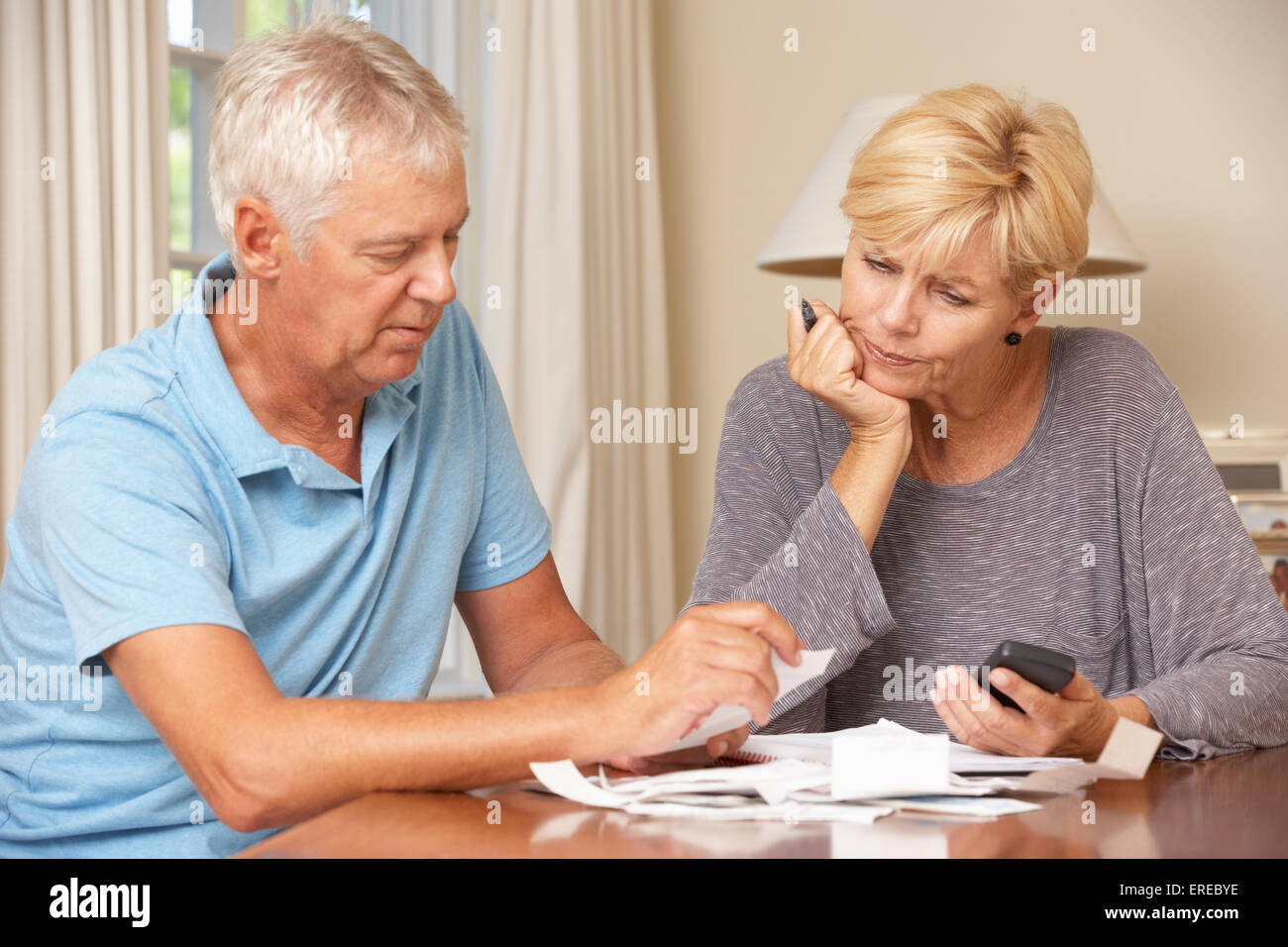 Worried Mature Couple Checking Finances And Going Through Bills Together Stock Photo