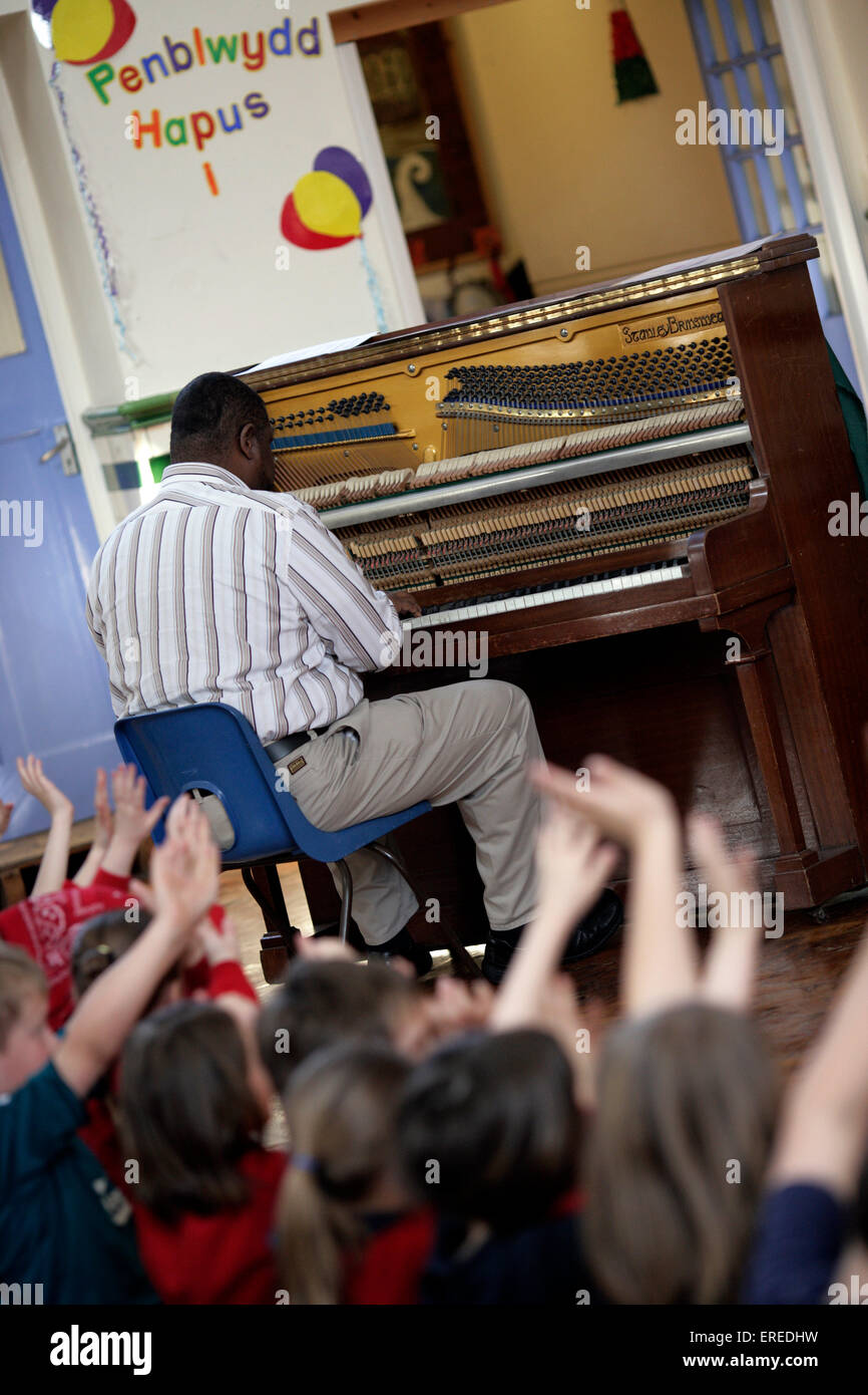 Music workshop with a painist playing in front of a class of children Stock Photo